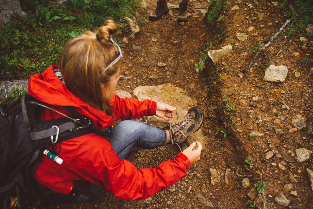 A hiker ties their shoelace.