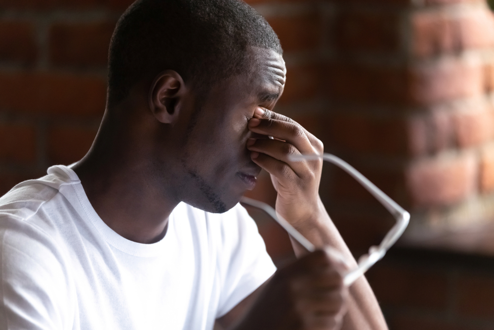 Man taking glasses off suffering from eye strain.