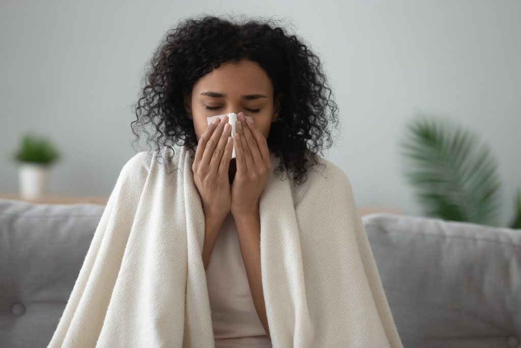 Sick woman at home blowing her nose