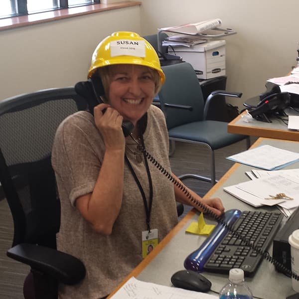 A photo of someone on the phone at The Portland Clinic wearing a yellow hard hat.