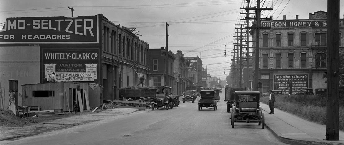 A black and white photo of cars driving on a busy street in historic Portland.