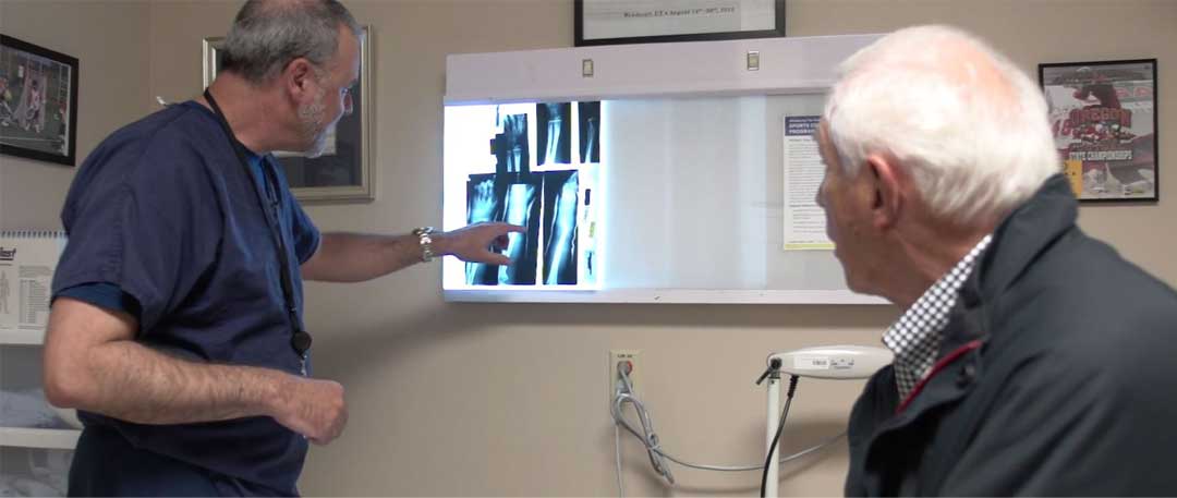 Dr. Sandmeier, left, shows Bob Dernedde, right, an x-ray of his kne