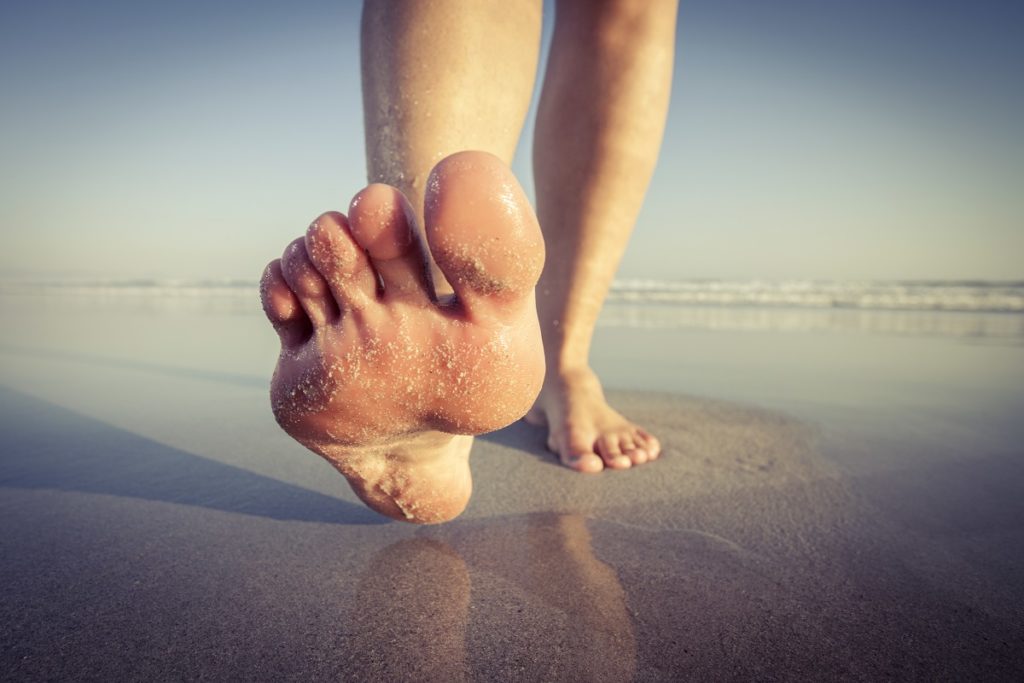 Woman's feet walking on wet sand