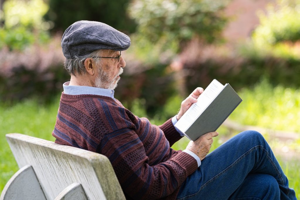 Senior man reading a book outside on a bench