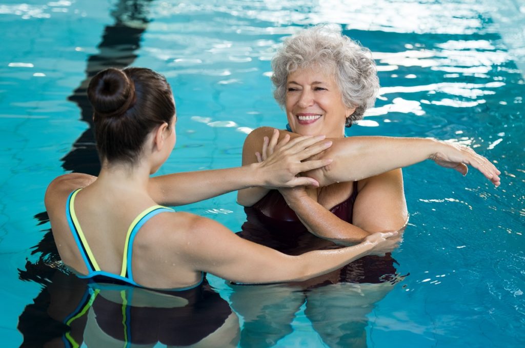 Senior woman stretching in swimming pool