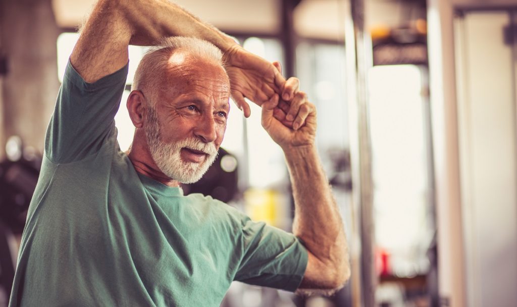 Senior man stretching at the gym