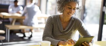 Older woman using digital tablet in cafe