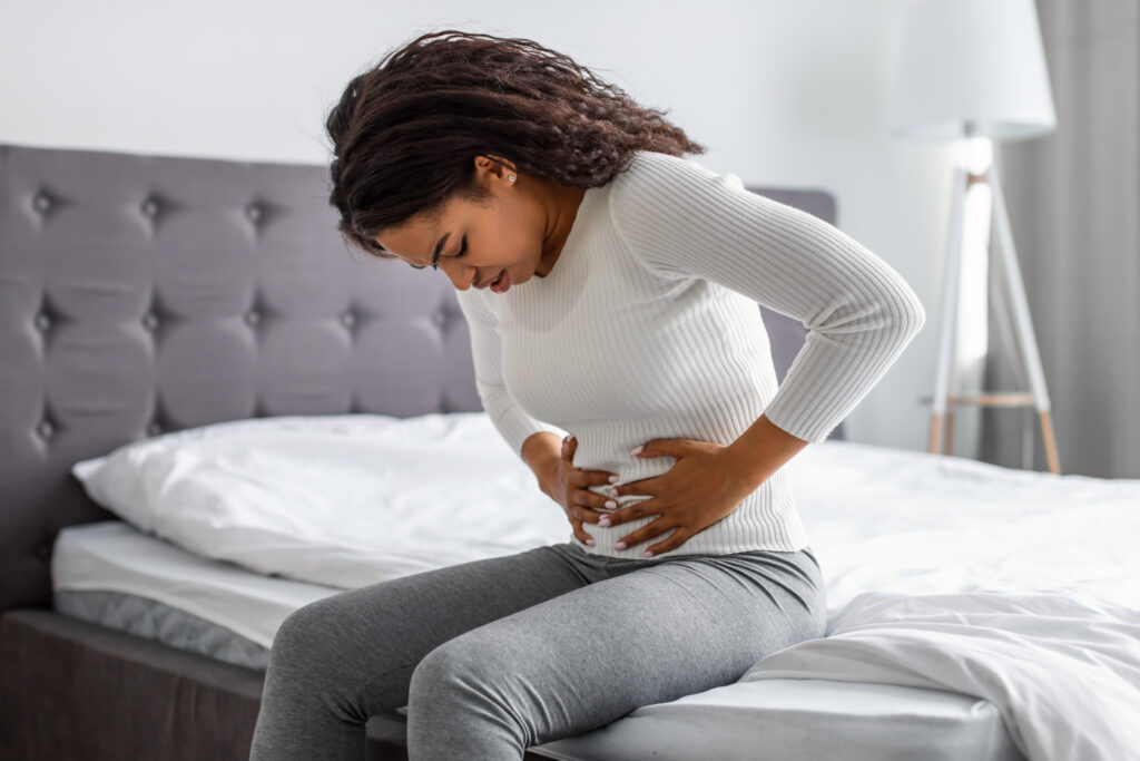 young black woman struggling with abdominal pain from endometriosis