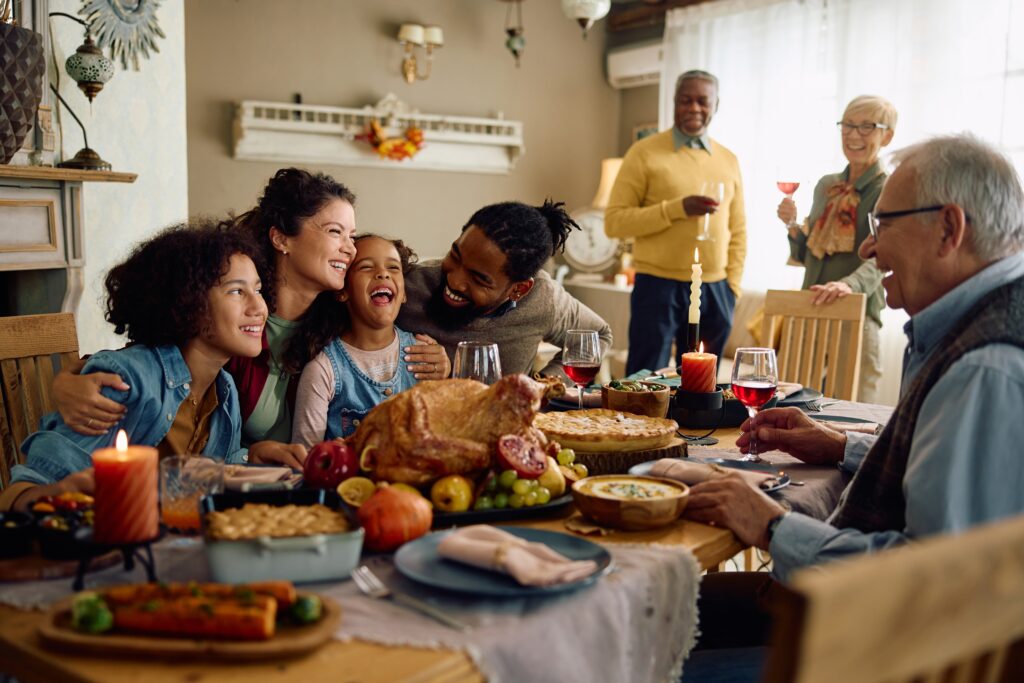 mixed racial family of varied ages gathers around a table for a shared meal