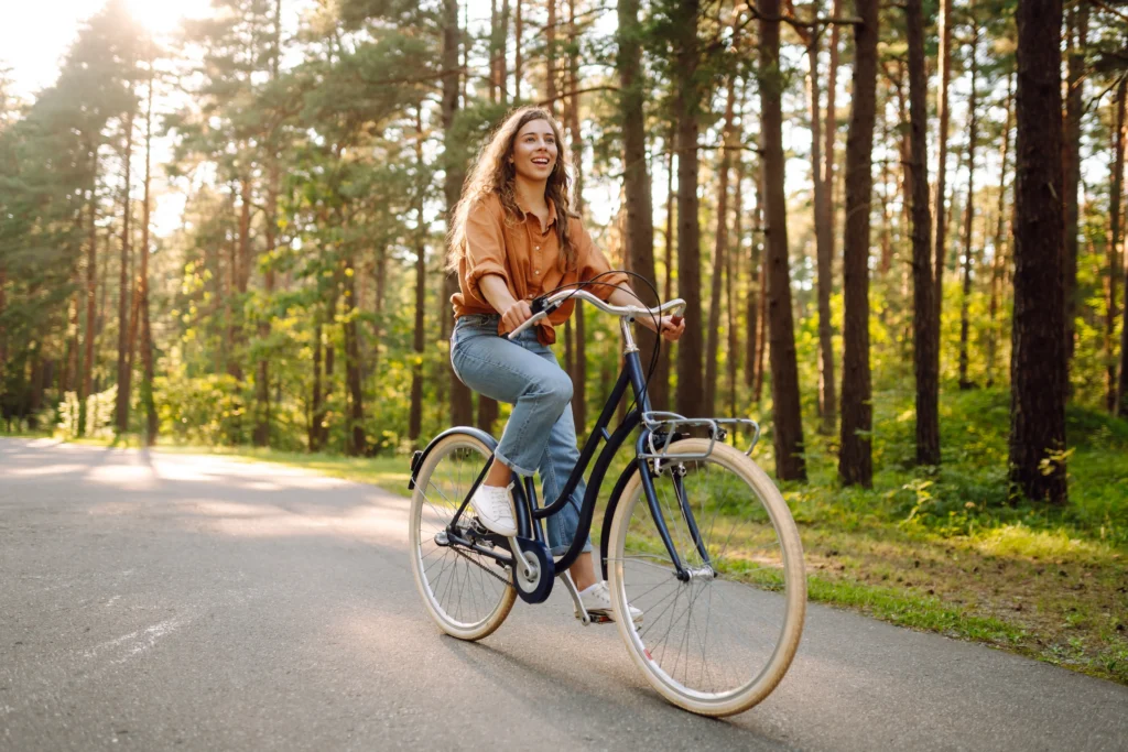 woman riding a black bike through a forested road